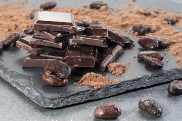 Broken dark chocolate and cocoa beans on a table