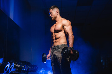 Strong muscular man hard working in gym. Fit athletic shirtless male model.