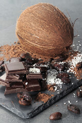 Broken dark chocolate and cocoa beans and coconut on the table
