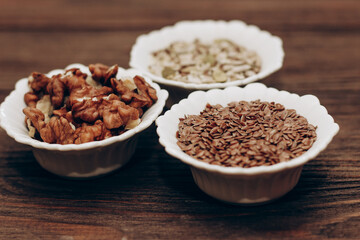 A mixture of sunflower, pumpkin and flax seeds with nuts in a bowl on a wooden table.