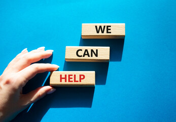 We can help symbol. Wooden blocks with words We can help. Beautiful blue background. Businessman hand. Business and We can help concept. Copy space.