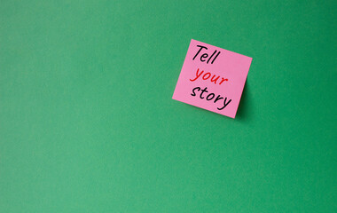 Tell your story symbol. Concept words Tell your story on pink steaky note. Beautiful green background. Business and Tell your story concept. Copy space.