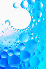 Fresh blue abstract macro image of swirling bright blue and green bubbles in water.