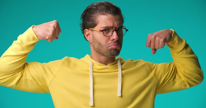 young casual man flexing his arms like a bodybuilder