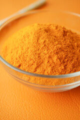  turmeric root powder in a bowl on orange background 