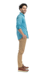 Fototapeta premium attractive casual guy with curly hair holding hands in pockets and smiling