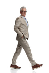 elegant man in suit with glasses walking with hands in pockets