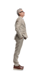 side view of adult in his 60s holding hands in pockets and standing in line