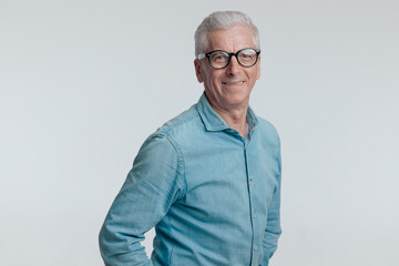 portrait of happy man in his 60s smiling and posing on grey background