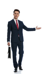 businessman holding briefcase and presenting to side