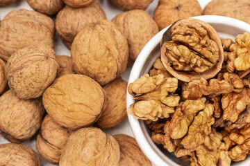 Walnut kernel in white bowl. Whole nuts on white.