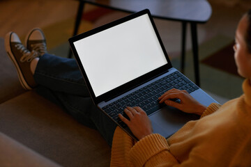 Side view young woman using laptop with white screen in cozy home setting