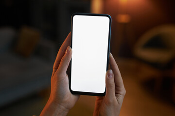 Close up female hand holding phone with white screen mockup at home