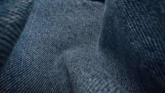 Macro shot blue denim jeans material. Slider dolly extreme close-up of clothing material, camera glides over fabric texture. Seams sewn with yellow threads. Shot with laowa 24mm lens