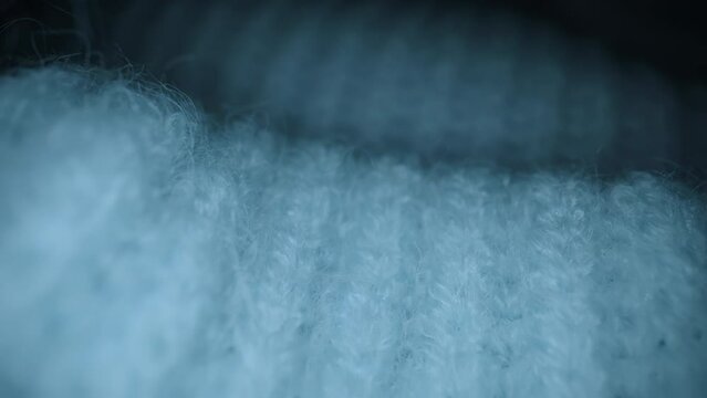 Macro shot of woolen fabric, knitted wool pullover. Slider dolly extreme close-up of clothing material blue woollens, woolens, wool fibers. Camera glides over warm winter clothing fabric texture