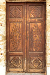 The background old beige stony wall with wooden door
