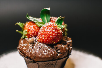 Chocolate muffin with Strawberry. Sprinkled powder decoration on the plate