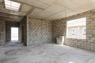 Construction of an individual residential building, view of a spacious room with a large window opening and a corridor leading to the front door