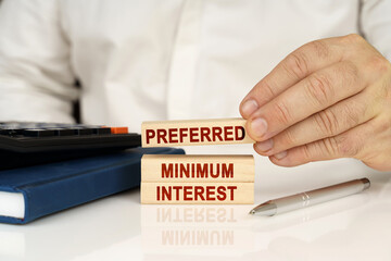 In the hands of a businessman, wooden blocks with the inscription - Preferred Minimum Interest