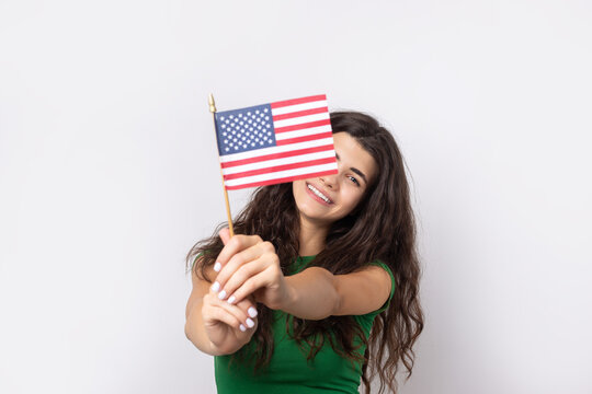 A young happy girl with a smile on her face holds an American flag in her hands. Symbol of patriotism and freedom.