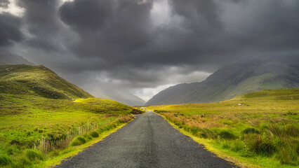 Road leading trough Doolough Valley, between Glenummera and Glencullin mountain ranges illuminated...