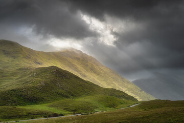 Doolough Valley, Glenummera and Glencullin mountain ranges illuminated by sunlight an partially covered by dark clouds, County Mayo, Ireland