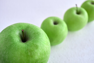 Green apples on a white background in a row diagonally. Apples in the snow.