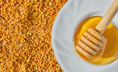 Bee pollen in granules and honey in a saucer with a spindle spoon, top view of environmentally...
