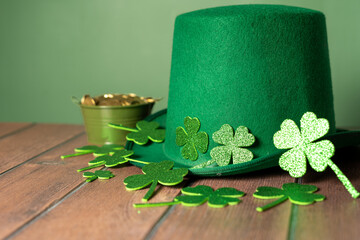 Celebrating St. Patrick's Day with a touch of luck: green hat, shamrocks and coins on a wooden table. High quality photo - Powered by Adobe