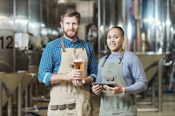 Two workers holding beer glasses at brewing factory