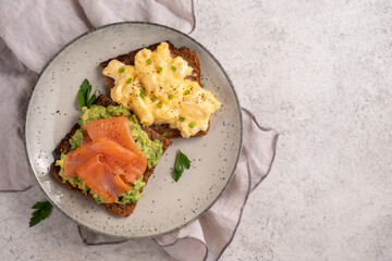 Scrambled eggs with smoked salmon and avocado on a whole wheat toast