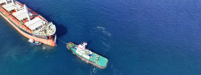 Aerial drone ultra wide top down photo with copy space of tanker ship guided by tug boat to...