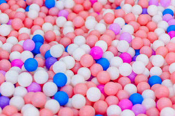Background, closeup texture of colored, multi-colored round plastic small balls on the playground for children's games. Photo, top view, copy space.