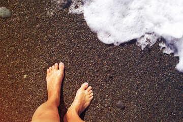Women's bare feet on a sandy beach near the sea on a sunny day. Vacation background