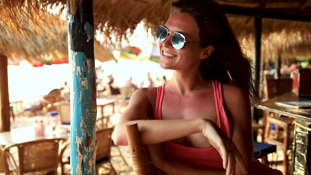 Woman wearing sunglasses sitting in the beach bar during hot summer day