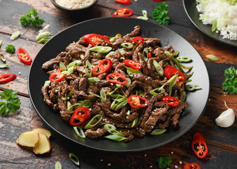 Korean beef Bulgogi with sesame seeds, chili and spring onion in a black plate