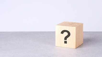 natural wooden cube with question mark on grey background