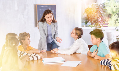 Fototapeta premium Portrait of female teacher giving lesson to children in school indoors
