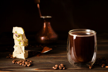 Fresh black coffee brewed in the correct narrow-necked cezve. Turkish sweets. Turkish halva with pistachios. Scattered coffee beans