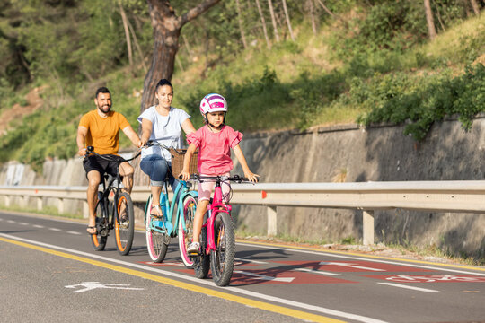 Mother, father and girl child having fun on vacation cycling near the sea. Family coastal bike ride.