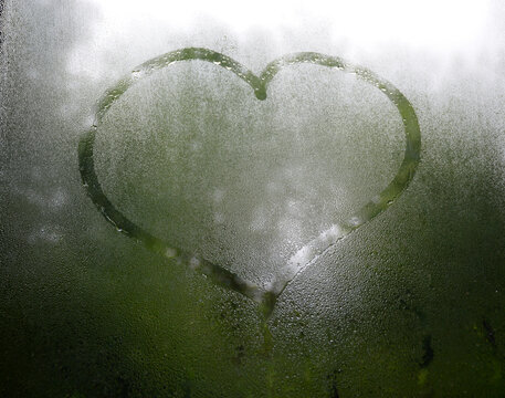 Autumn rain and a heart painted on misted glass. a symbol of love, devotion, friendship and sympathy. confession of feelings expressed in the picture on the window