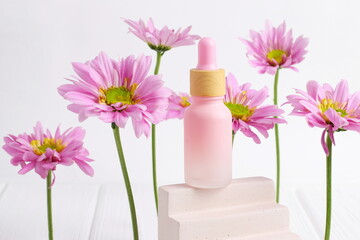 Cosmetic bottle on wooden table with pink daisy flowers