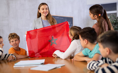Fototapeta na wymiar Teacher with flag of Morocco tells story of the emergence of the state