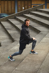 Young man stretching hands before jogging in sports clothes and headphones on his head