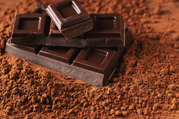 Dark and milk chocolate with nuts on a dark background sprinkled with cocoa powder.
