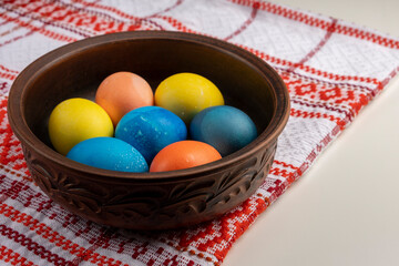 Colorful Easter eggs in plate on white table. Easter concept