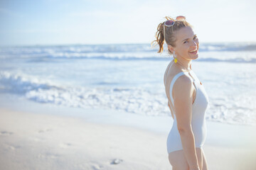 Fototapeta na wymiar smiling elegant woman in white swimwear at beach relaxing