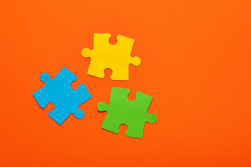 Teamwork concept - Three puzzle pieces of blue, green and yellow color on orange background