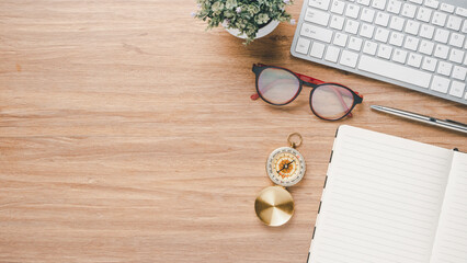 Wooden desk workplace with keyboard computer, eyeglass, pen and notebook, Top view flat lay with copy space.