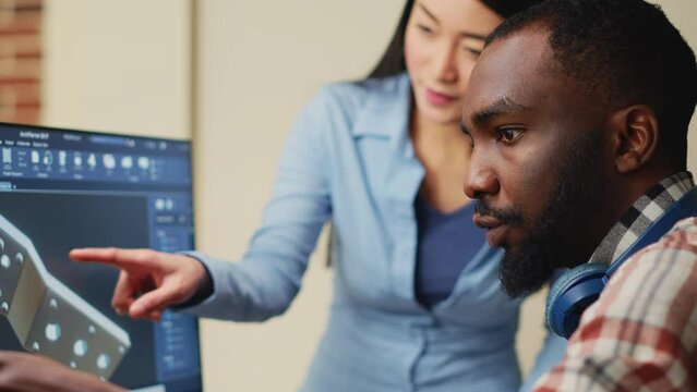 African american 3d designer creating industrial engine product on cad software, brainstorming mechanial ideas with asian colleague. Male employee developing professional prototype